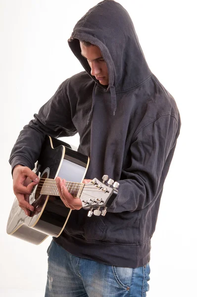 Young man dressed  in hoodie try to understand how to play acous — Stock Photo, Image