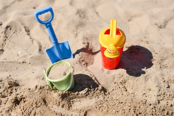 Buntes Sommer-Strandspielzeug, Eimer, Sprinkler und Schaufel auf Sand — Stockfoto