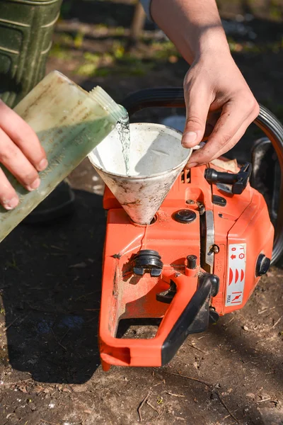 Hand refilling the chainsaw with fuel — Stock Photo, Image