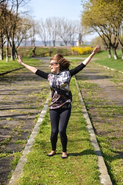 Bardzo młoda kobieta, skoki na zielonej trawie i uśmiechnięta pełna jo — Zdjęcie stockowe