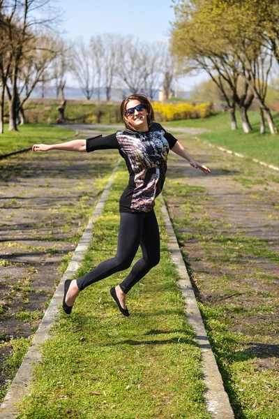 Pretty young woman jumping on green grass and smiling full of jo Stock Photo