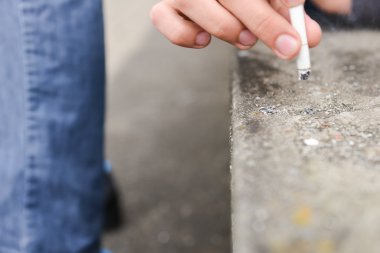 Genç bir adamın elini bir merdiven üzerinde sigara söndürmek