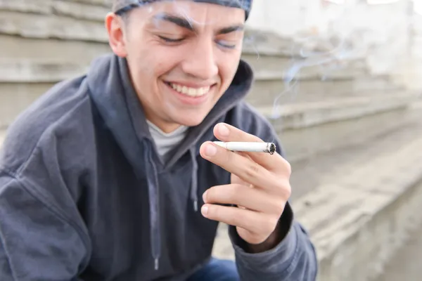 Imagen sobre fumar. joven se ríe y fuma un cigarro — Foto de Stock