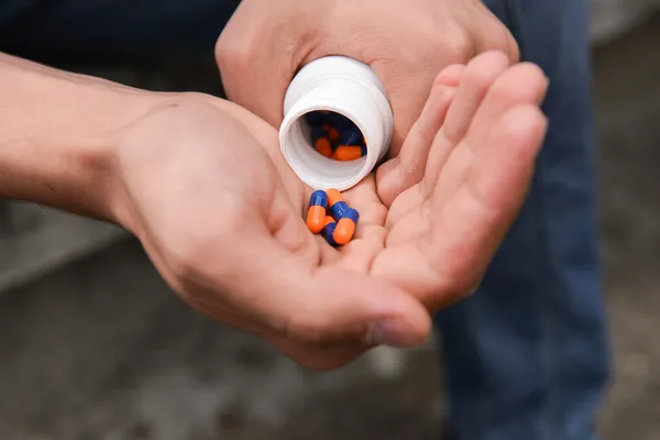 Depressed teenage boy with many tablets in hand, wants to take a — Stock Photo, Image