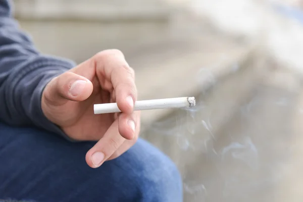 Jovem mão masculina segurando um cigarro — Fotografia de Stock