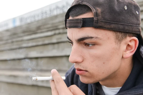Мальчик-подросток курит на открытом воздухе. Концепция молодых людей — стоковое фото