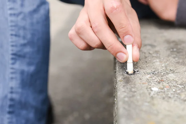 Rękę młodego człowieka zgasić papierosa na schody — Zdjęcie stockowe