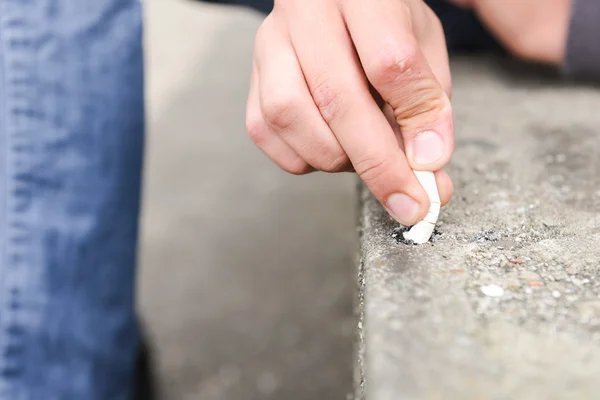 Rukou mladého muže uhasit cigaretu na schody — Stock fotografie