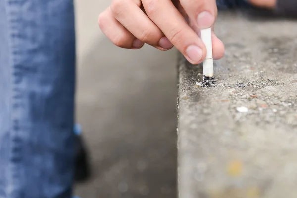 Hand of a young man extinguish cigarette on a stair — Stock Photo, Image