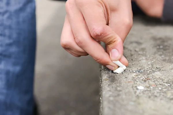 一名年轻男子手熄灭香烟在楼梯上 — 图库照片