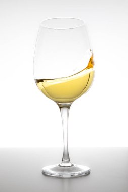 Beyaz arka planda camda dönen beyaz şarap.