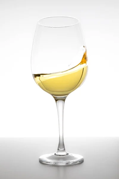 Beyaz arka planda camda dönen beyaz şarap.