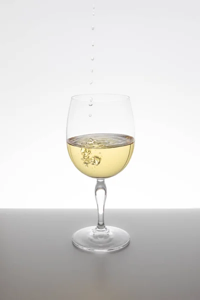 Beyaz arka planda cam içine düşen beyaz şarap