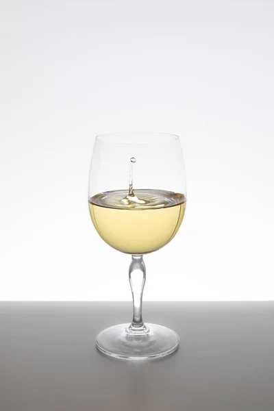 Beyaz arka planda cam içine düşen beyaz şarap