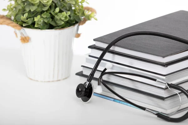 Tıp öğrencileri için ders kitapları, steteskop beyaz ve yeşil bitki arka planında izole edilmiş..