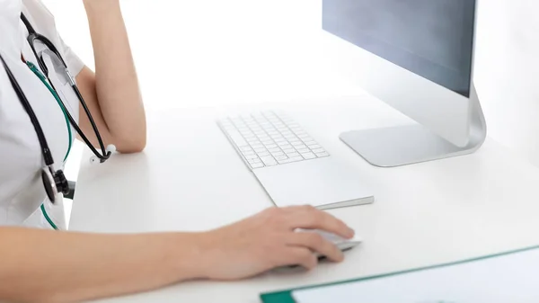 Doktor masasında bilgisayara bakıyor.