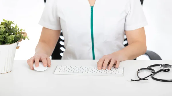 Doktor masasında bilgisayarda yazıyor.