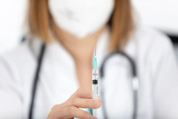 Doktora yakın çekim, masasında bir iğne ile hemşire..