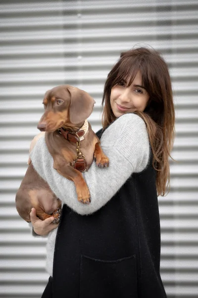 Sokakta küçük Dachshund köpeğini okşayan bir kız.