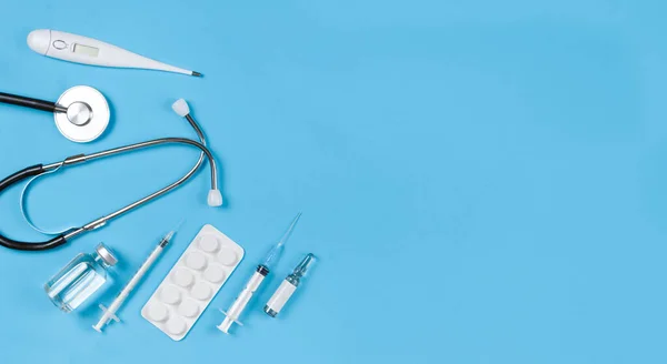 Stethoscope,vials, syringe, thermometer, pills blister on a blue background with copy space. — Stock Photo, Image