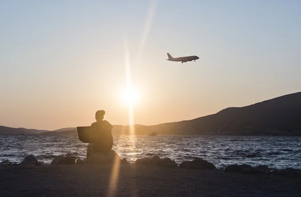 Frau arbeitet am Laptop mit Sonnenuntergang am Strand Stockbild