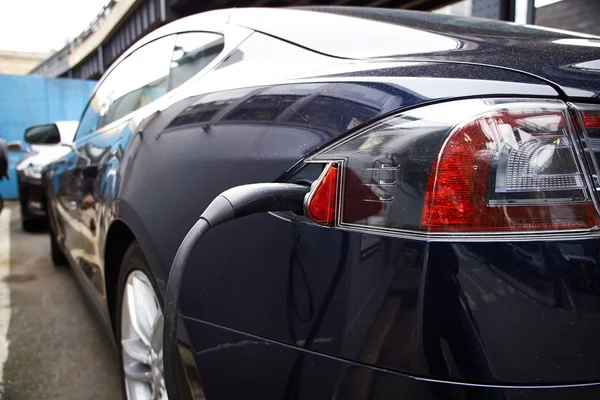 En tesla motors model s laddar på en allmän parkeringsgarage. — Stockfoto