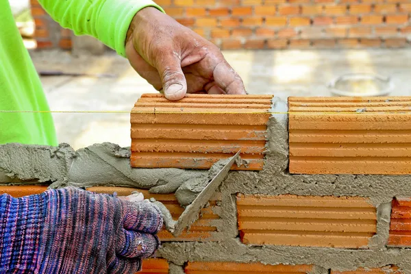 Worker create a brick wall with trowel and cement mortar — Stock Photo, Image