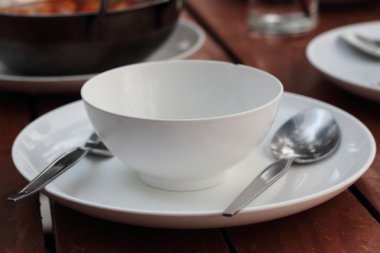 boş bir fincan tabak, çatal ve kaşık ahşap bir masa üzerinde