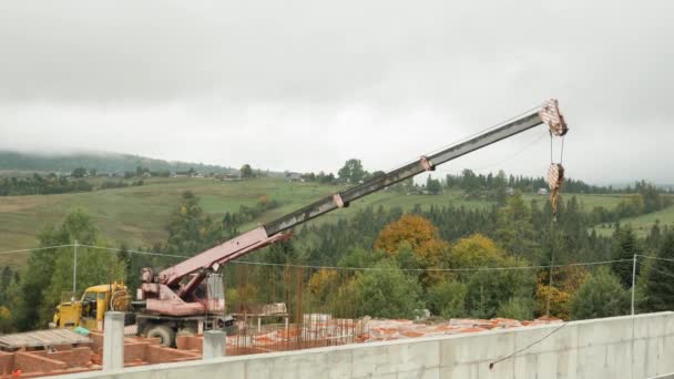 Żuraw budowlany pracujący nad budową w górach. Żuraw załadowczy pracujący na placu budowy — Wideo stockowe