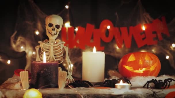 Skelett, orange belysning pumpa och halloween symboler i ljus och rök mot mörk bakgrund — Stockvideo