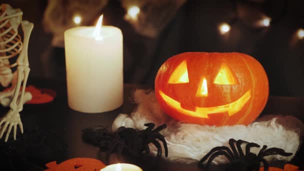 Interior Halloween com abóbora e vela no escuro. Abóbora laranja esculpida brilhando dentro — Vídeo de Stock