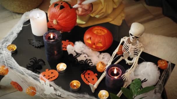 ハロウィンの飾りだ。ろうそくの明かりの下でテーブルの上に伝統的なハロウィーンのシンボル — ストック動画