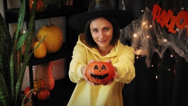 Halloween. Kvinna i häxhatt med snidad pumpa. Jack-O-Lantern. Dekorerat rum för Halloween — Stockvideo