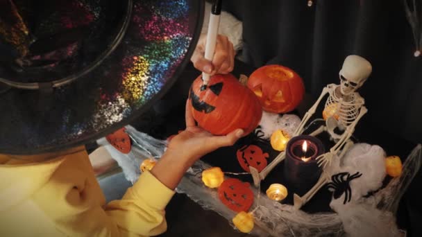 Glad halloween. Firar halloweenfesten. Flicka målning skrämmande pumpa ansikte — Stockvideo