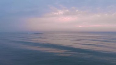 Deniz doğumu. Dalgalı ve plajlı güzel pembe gün batımı. Doğa manzarası