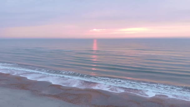 Tengeri naplemente. Gyönyörű rózsaszín napkelte a tenger felett nagy hullámokkal. Homokos strand naplementekor — Stock videók