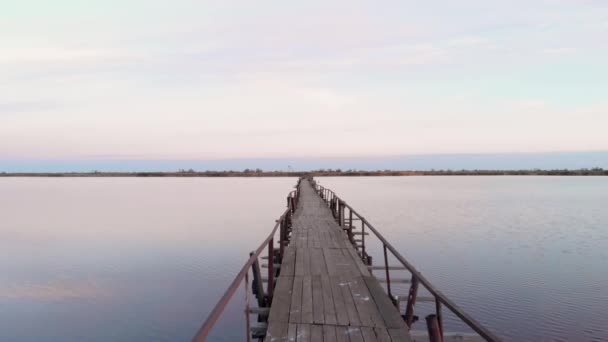 해 가 뜨면 강하구 에는 고요 한 물 이 있습니다. 비어 있는 다리가 있는 호수 위의 일몰 광경 — 비디오