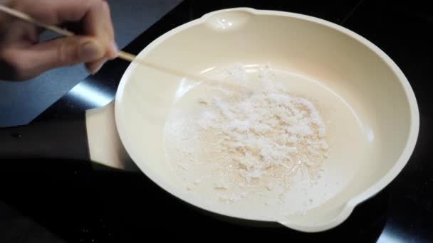 Жіночі руки перемішують білий цукор у гарячій сковороді. карамелізований цукор — стокове відео