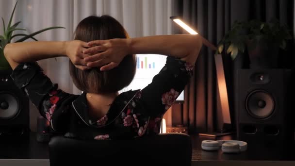 Vrouw ontspannen in het kantoor op de avond, zitten op stoel hand in hand achter hoofd — Stockvideo