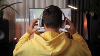 Kulaklıklı oyuncu karanlık odada bilgisayar ekranının önünde oturmuş video oyunu oynuyor.