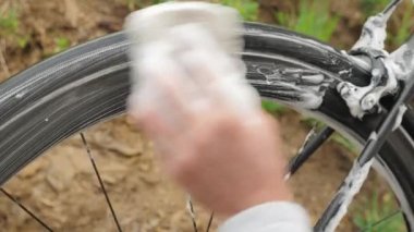 Bisiklet yıkama. Adam bisiklet tekerleğini sabun köpüğüyle yıkıyor. Bisikleti dışarıda yıka.