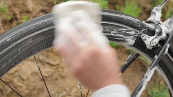 Lavaggio biciclette. L'uomo lava ruota bici con schiuma di sapone. Lavare la bici fuori — Video Stock