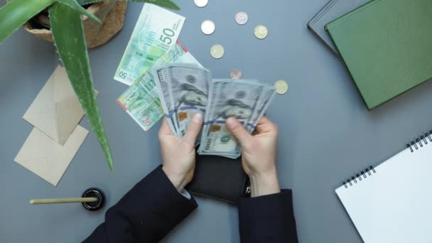 Γυναίκα βάζει χαρτονομίσματα των 100 δολαρίων στο πορτοφόλι στο τραπέζι. Χρηματοδοτική έννοια — Αρχείο Βίντεο