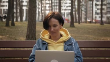 Parkta uzaktan çalışan çekici bir kadın. Kız öğrenci bahar parkında internetten ders çalışıyor.