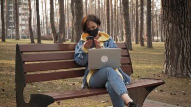 Spring Park 'ta koruyucu maskeli bir kadın. Kişisel izolasyon, serbest çalışma, uzak çalışma