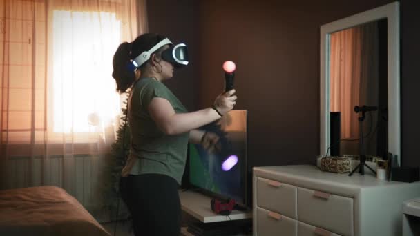 Mulher está usando fone de ouvido realidade aumentada, jogando jogos, usando joysticks — Vídeo de Stock