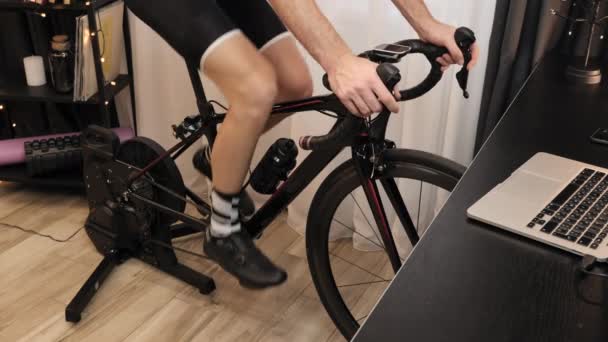Pernas masculinas estão girando pedais em bicicleta estacionária. Ciclismo interno. Exercício de fitness — Vídeo de Stock