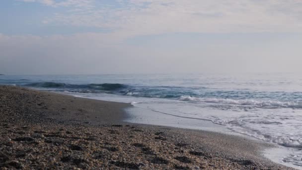 Fale morskie i plaża. Fale pluskające i tworzące białą pianę, docierające do żwirowej plaży — Wideo stockowe