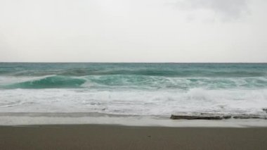 Güçlü deniz dalgaları su yüzeyine sıçrıyor ve sahile çarpıyor.