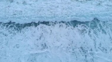 Büyük beyaz köpüklü deniz dalgaları, üst manzara. Okyanus dalgaları kayalara çarpıyor.